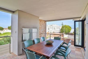 Ein Balkon mit Tisch und Stühlen, einem Kühlschrank und einer Steinsäule.