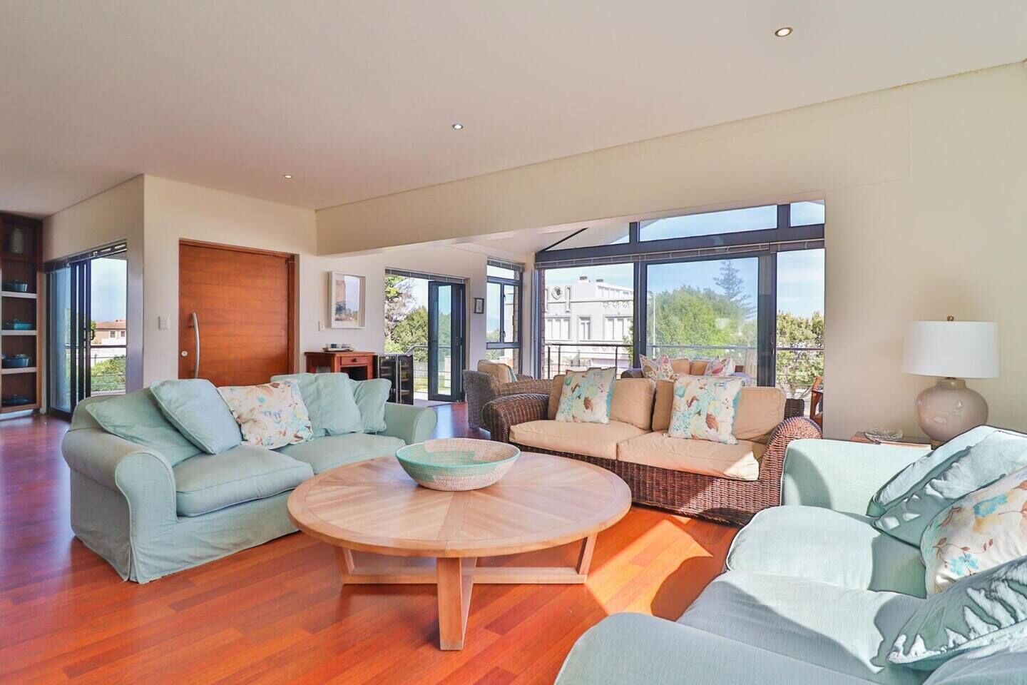 A spacious living room with a large window, a round wooden coffee table, and a sofa set.
