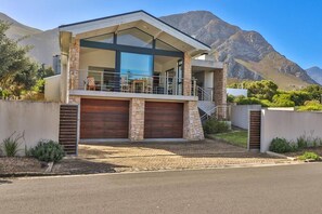 Uma casa moderna de dois andares com varanda, fachada de pedra e garagem.