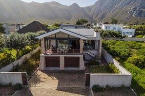 A modern two-story house with a balcony, a garage, and a view of mountains.