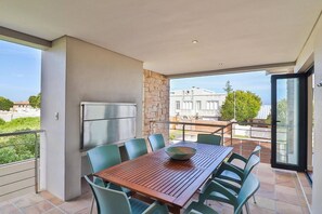 A balcony with a table and chairs, a refrigerator, and a stone wall.