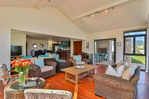 A spacious living area with wicker furniture, a wooden coffee table, and a television in the background.