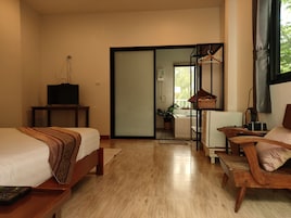A hotel room with a bed, a TV on a stand, a desk with a chair, a window, and a sliding door leading to a bathroom.
