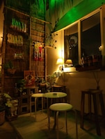 A cozy room with a bamboo wall, a small table with a chair, and a window with a view of the night sky.