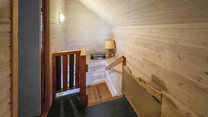 A wooden interior with a staircase, a lamp, and a radio on a shelf.