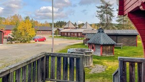 A rustic wooden cabin with a thatched roof, surrounded by a grassy area and a small wooden dock.