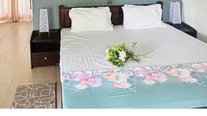 Une chambre à coucher avec un lit, des tables de chevet, une couvre-lit à motifs floraux et deux tableaux encadrés accrochés au mur.