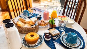 A breakfast setting with a variety of food items, including pastries, bread, and beverages, arranged on a table with a placemat.