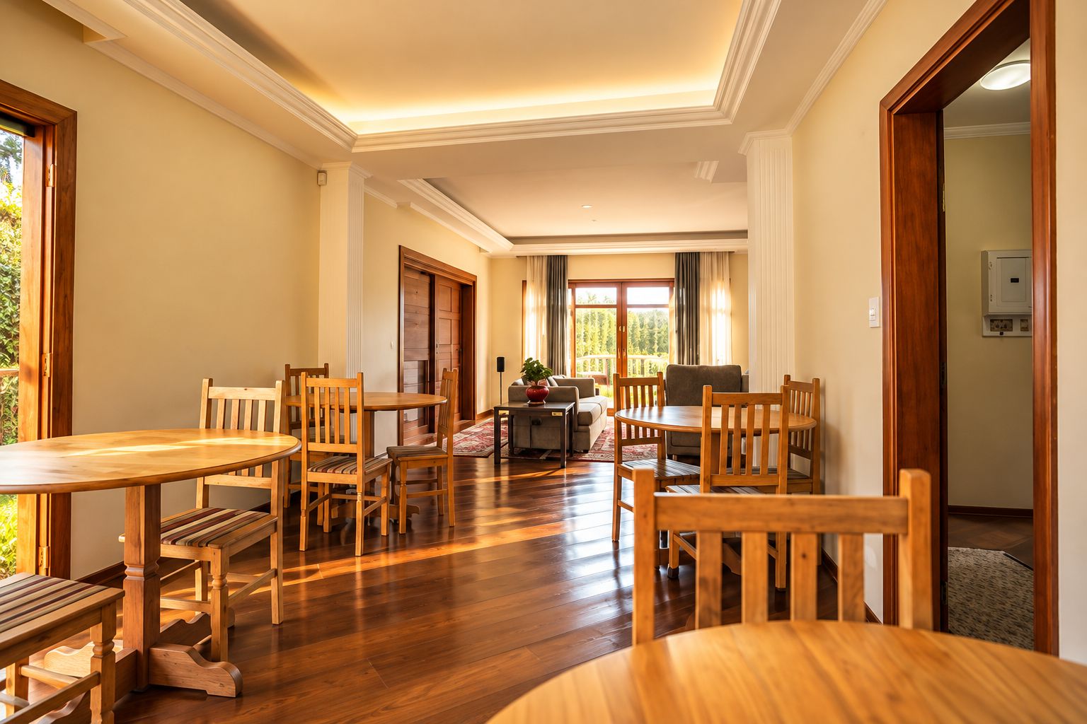 Un comedor amplio con mesas y sillas de madera, un sofá y vistas al exterior.