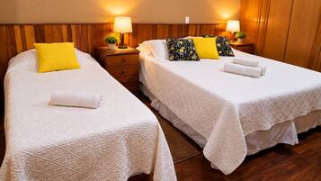 Two single beds with white linens, a wooden headboard, bedside tables with lamps, and a small potted plant.