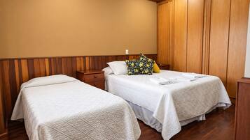 A hotel room with two beds, wooden paneling on the walls, and a wooden floor.