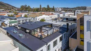A modern building with a rooftop terrace featuring a glass enclosure and solar panels. - Inner City Apartment 2 with Car Park + Rooftop Balcony (Nelson)