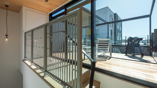 A modern interior with a wooden ceiling, a staircase, and a view of the outside. - Inner City Apartment 2 with Car Park + Rooftop Balcony (Nelson)