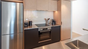 A modern kitchen with stainless steel appliances, wooden cabinets, and a built-in oven. - Inner City Apartment 2 with Car Park + Rooftop Balcony (Nelson)