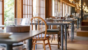 A restaurant with wooden chairs and tables, large windows, and hanging lights. - Yumejuya (Yugawara)