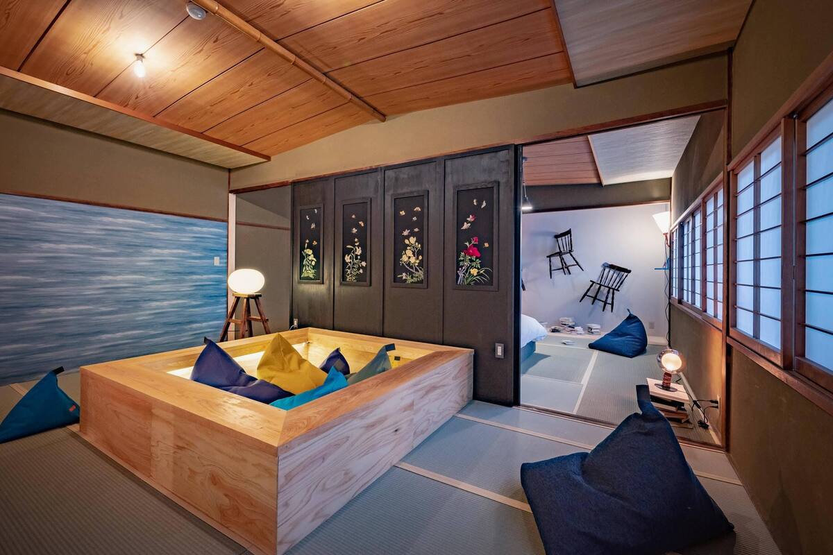A traditional Japanese room with tatami flooring, a wooden bathtub, and sliding doors with floral designs.