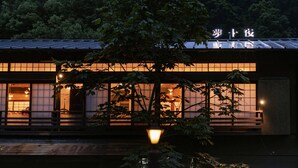 A traditional Japanese building with a sign in Japanese characters, large windows, and a tree in front. - Yumejuya (Yugawara)