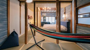 A room with a hammock, tatami flooring, a bed, and a view of another room with a desk and chair. - Yumejuya (Yugawara)