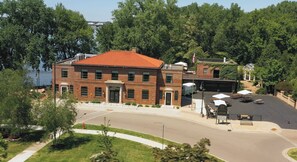 Un bâtiment en briques avec un toit rouge, un parking et une étendue d’eau en arrière-plan.