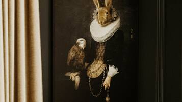 A framed artwork of a rabbit in a dress with an eagle and a chain.