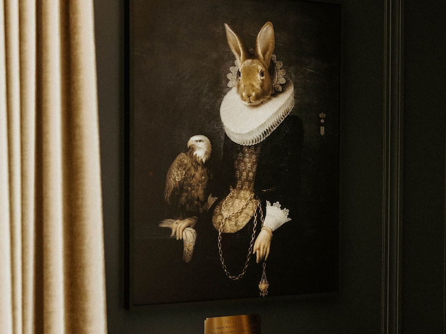 A framed artwork of a rabbit in a dress with an eagle and a chain.
