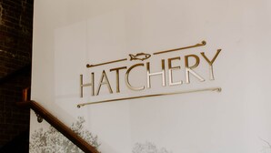 Ein Wandschild mit der Aufschrift "HATCHERY" in einer verzierten Schrift.