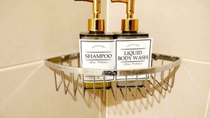 Une étagère de salle de bain contenant deux bouteilles de shampoing et de gel douche, dont le contenu a été versé à la main.