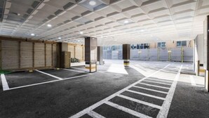 A parking garage with a geometric ceiling design, marked parking spaces, and a view of the outside through the garage doors. - Incheon BEYOND HOTEL (Incheon)