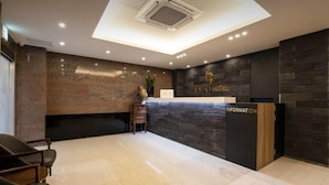A hotel reception area with a modern design, featuring a reception desk, a seating area with chairs, and a ceiling with recessed lighting. - Incheon BEYOND HOTEL (Incheon)