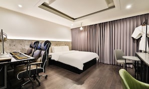 A modern hotel room with a bed, a desk with a chair, a massage chair, and a small table with a chair. - Incheon BEYOND HOTEL (Incheon)