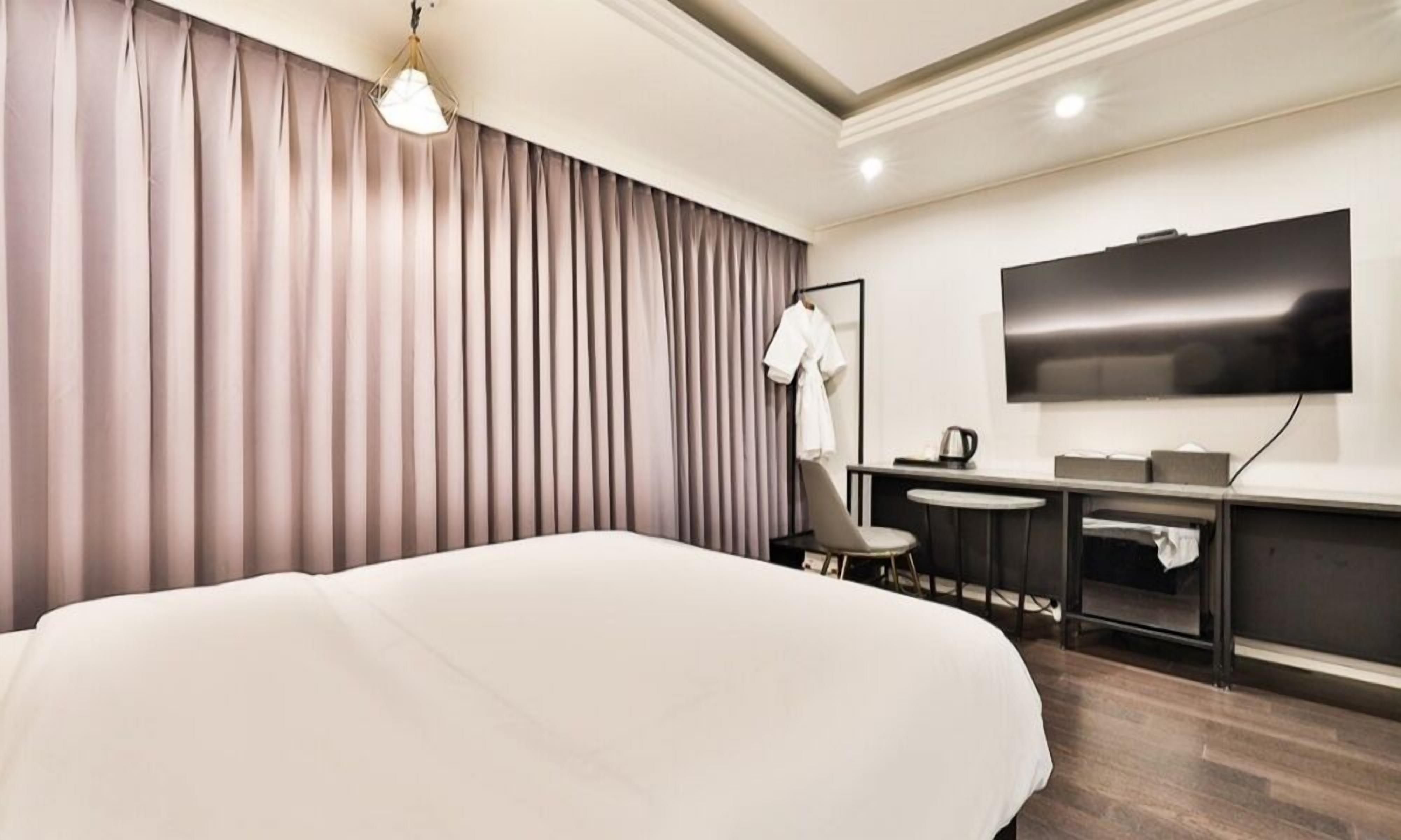 Een moderne hotelkamer met een groot bed, een bureau, een stoel, een flatscreen televisie en een kledingkast.