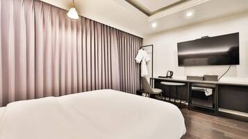 Een moderne hotelkamer met een groot bed, een bureau, een stoel, een flatscreen televisie en een kledingkast.