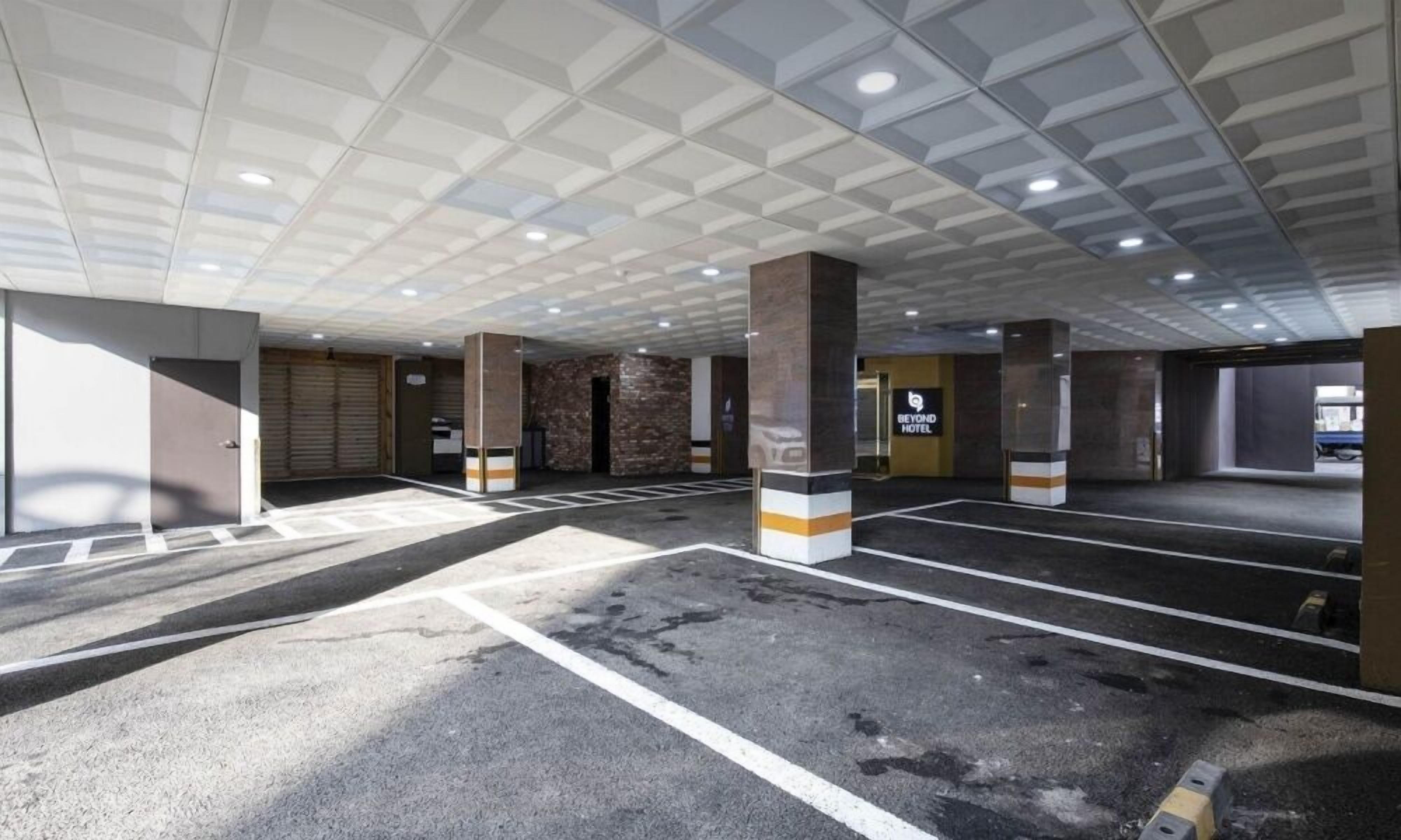 A parking garage with multiple levels, marked parking spaces, and a sign for 'Beyond Hotel'.