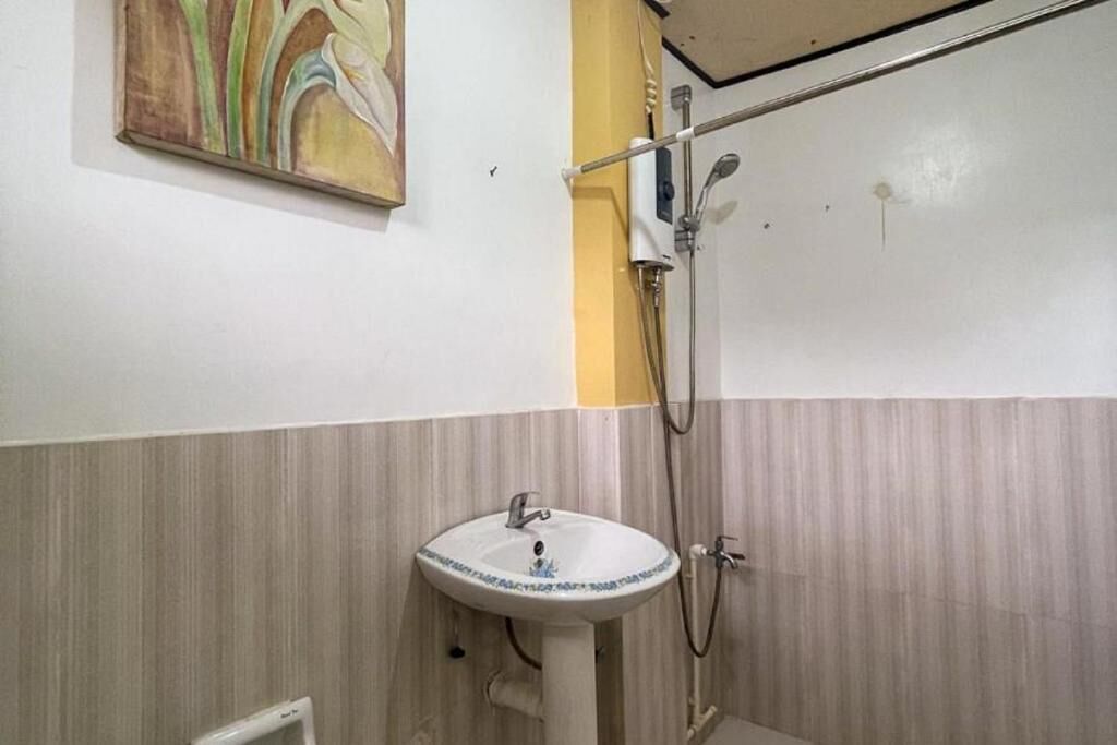 A bathroom with a white sink, a shower, and a painting on the wall.
