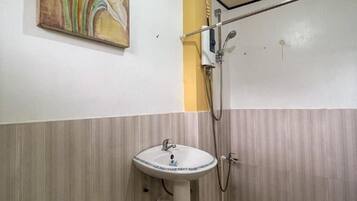 A bathroom with a white sink, a shower, and a painting on the wall.