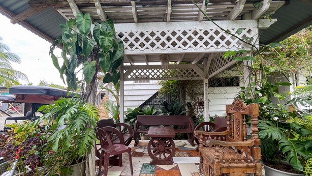Un área de patio al aire libre con un banco de madera, sillas y una mesa.