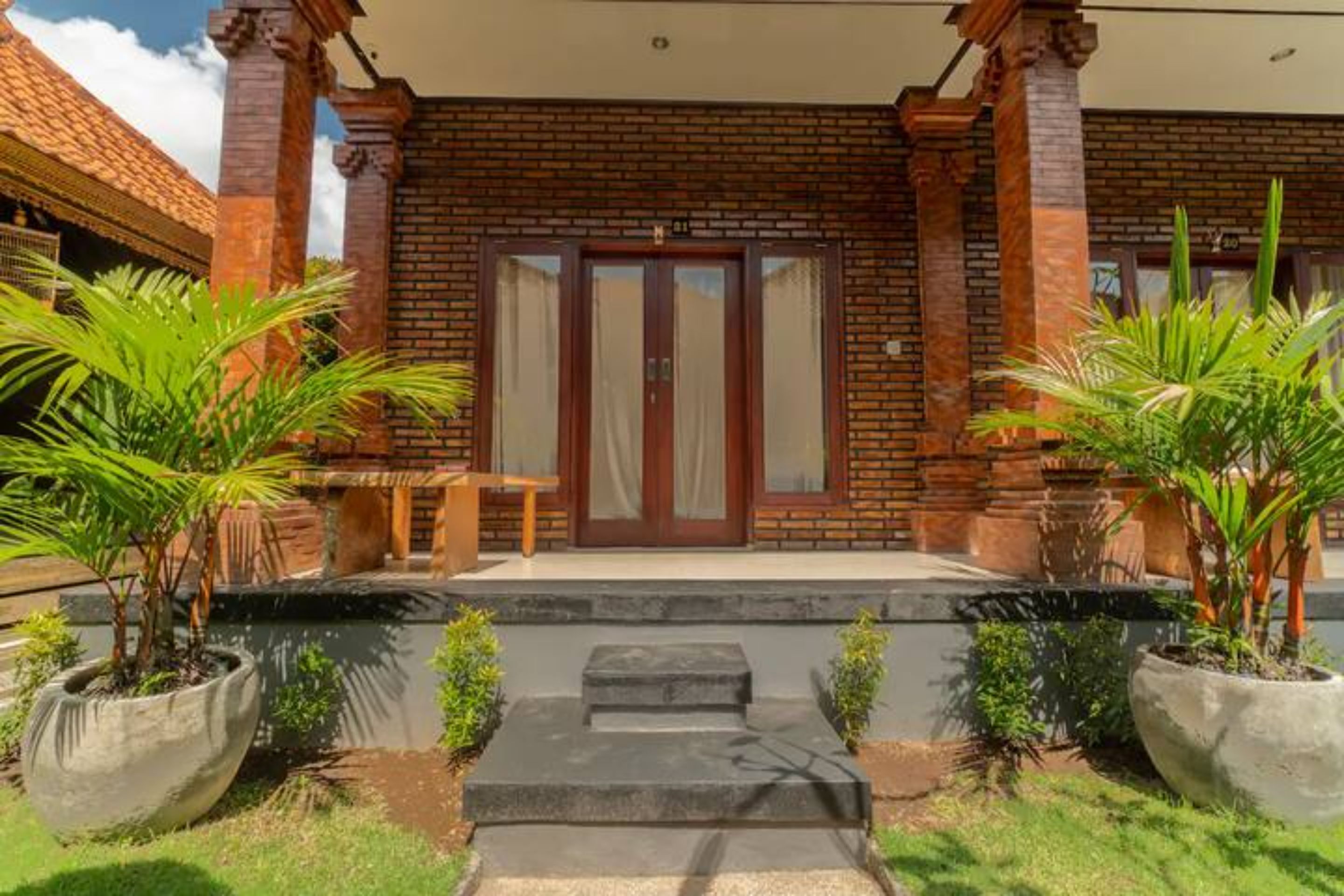A brick building with a wooden bench and potted plants in front.