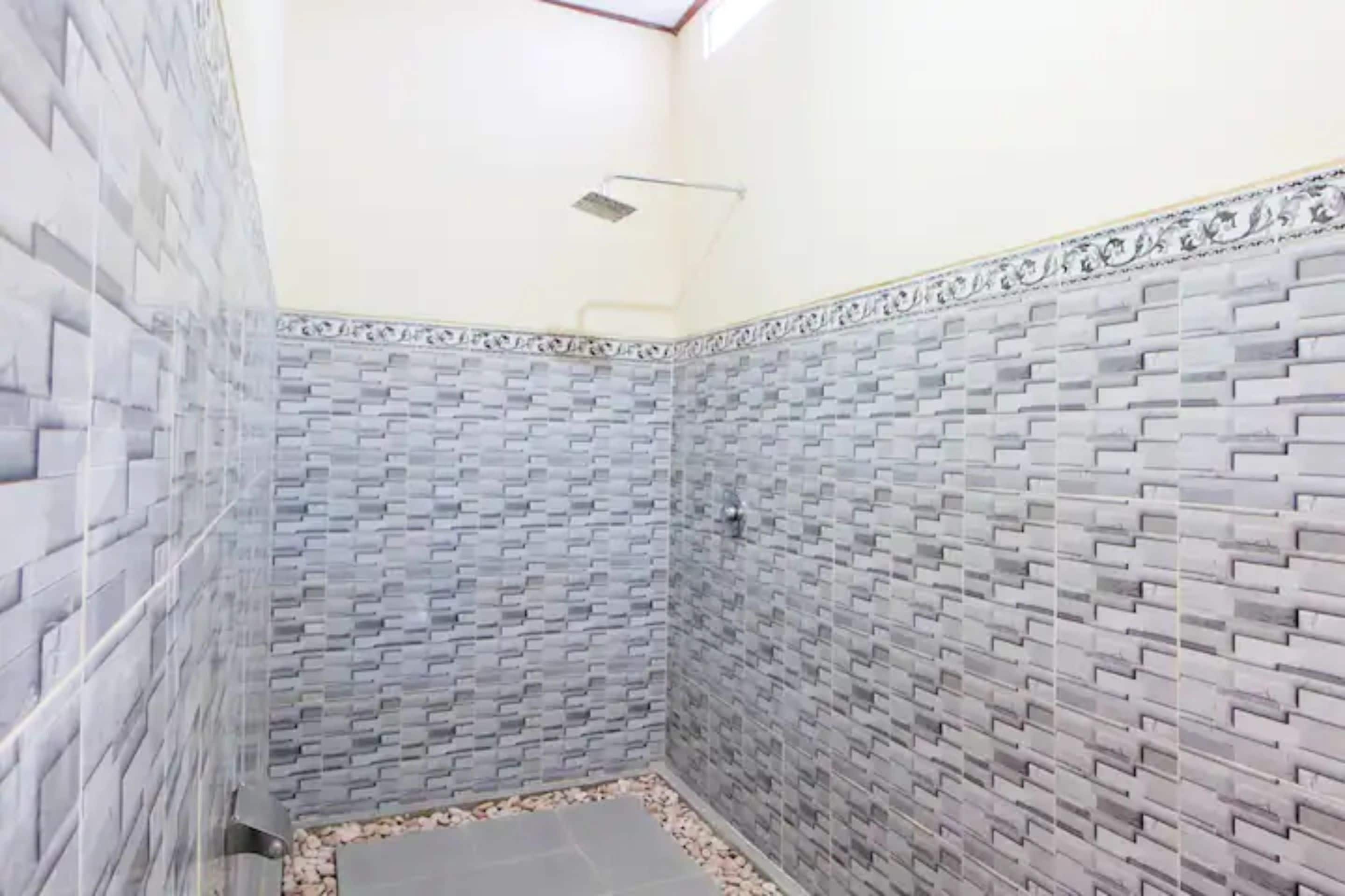 A bathroom with a tiled wall featuring a brick pattern and a decorative border.