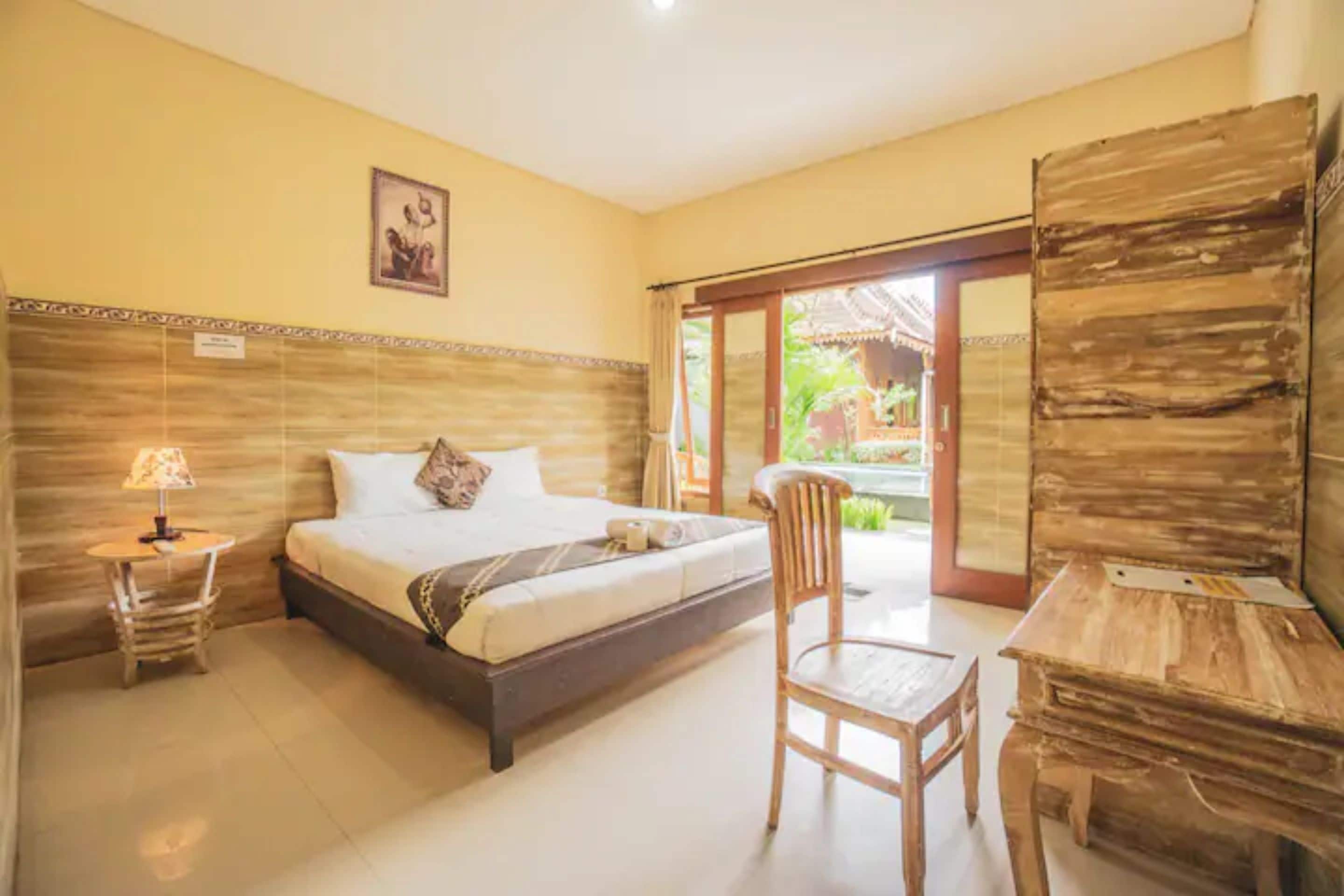 Un dormitorio con cama, una silla, un escritorio y vistas al exterior.