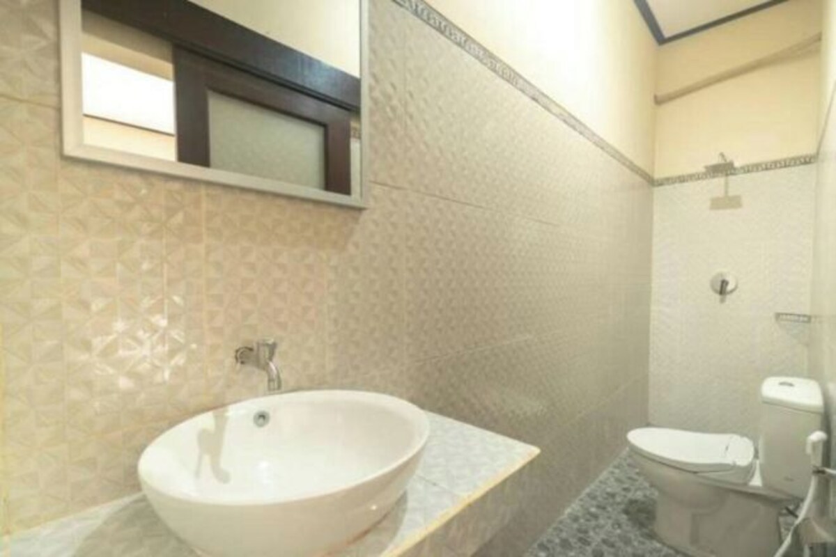 A bathroom with a large white sink, a toilet, and a shower area.
