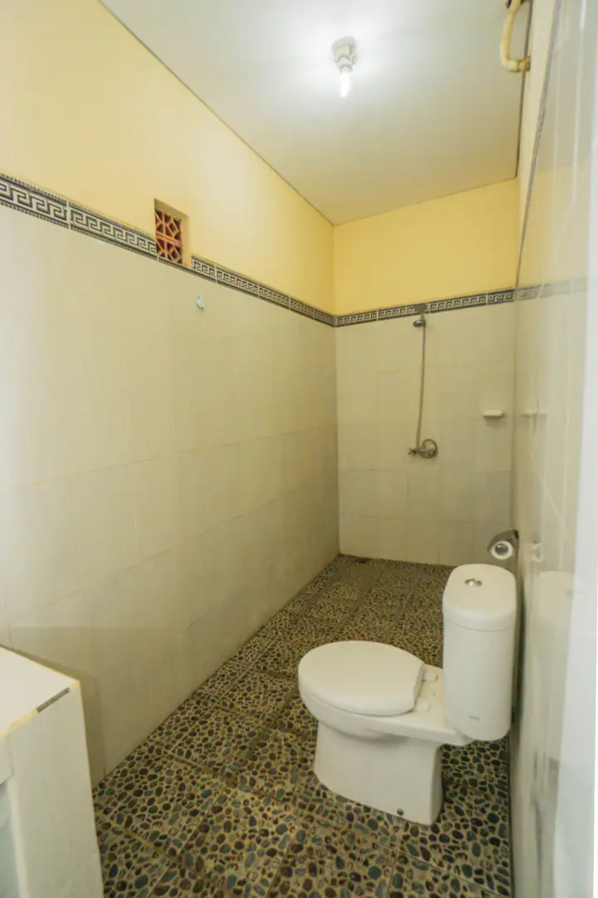 A small, tiled bathroom with a shower, a toilet, and a sink.