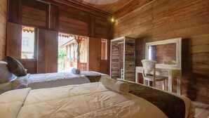 Ein Zimmer mit Holzboden, zwei Betten, einem kleinen Tisch und einem Stuhl.
