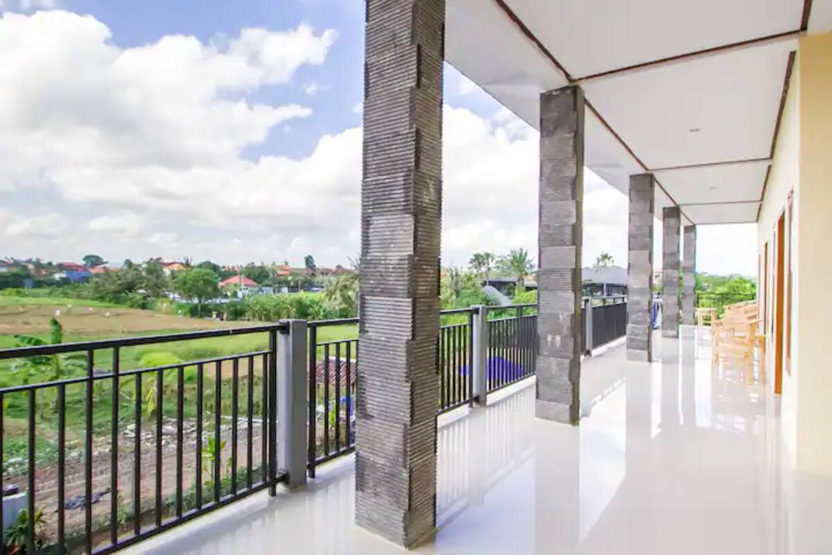 A spacious balcony with a view of a green landscape and distant buildings.