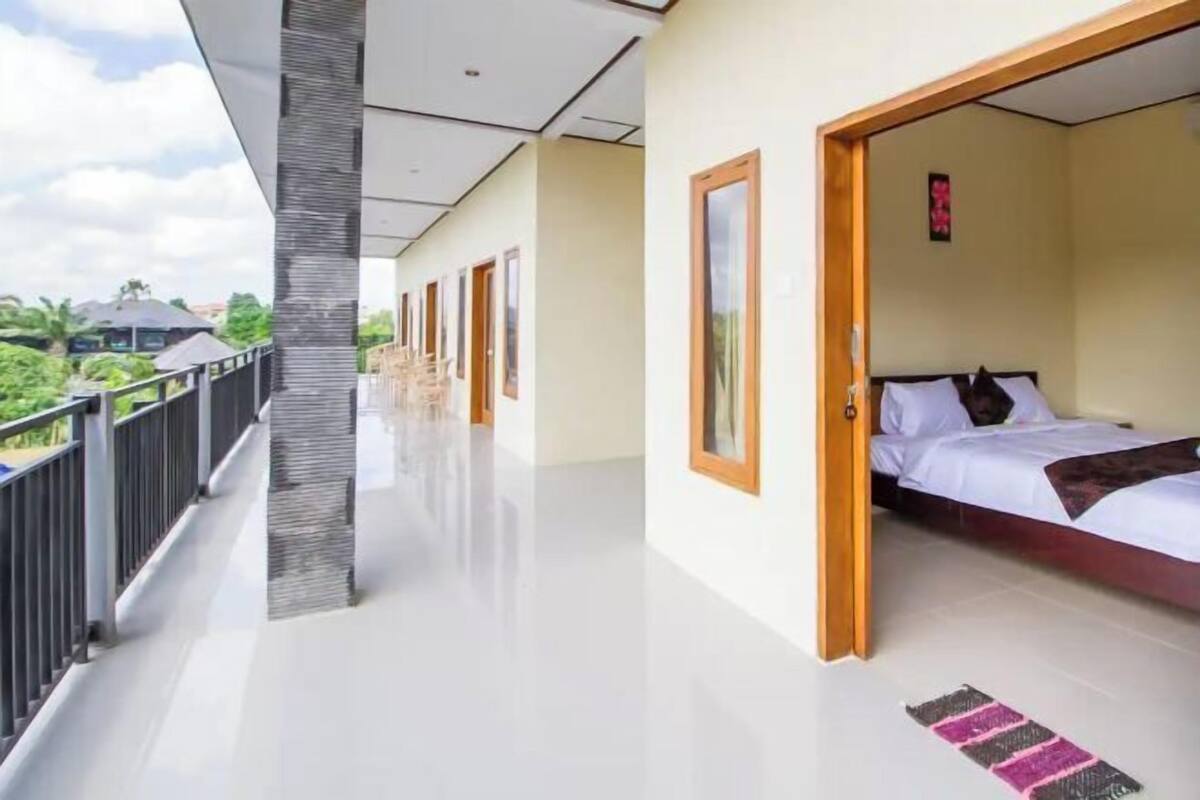 A hotel room with a balcony, a bed, and a view of greenery.