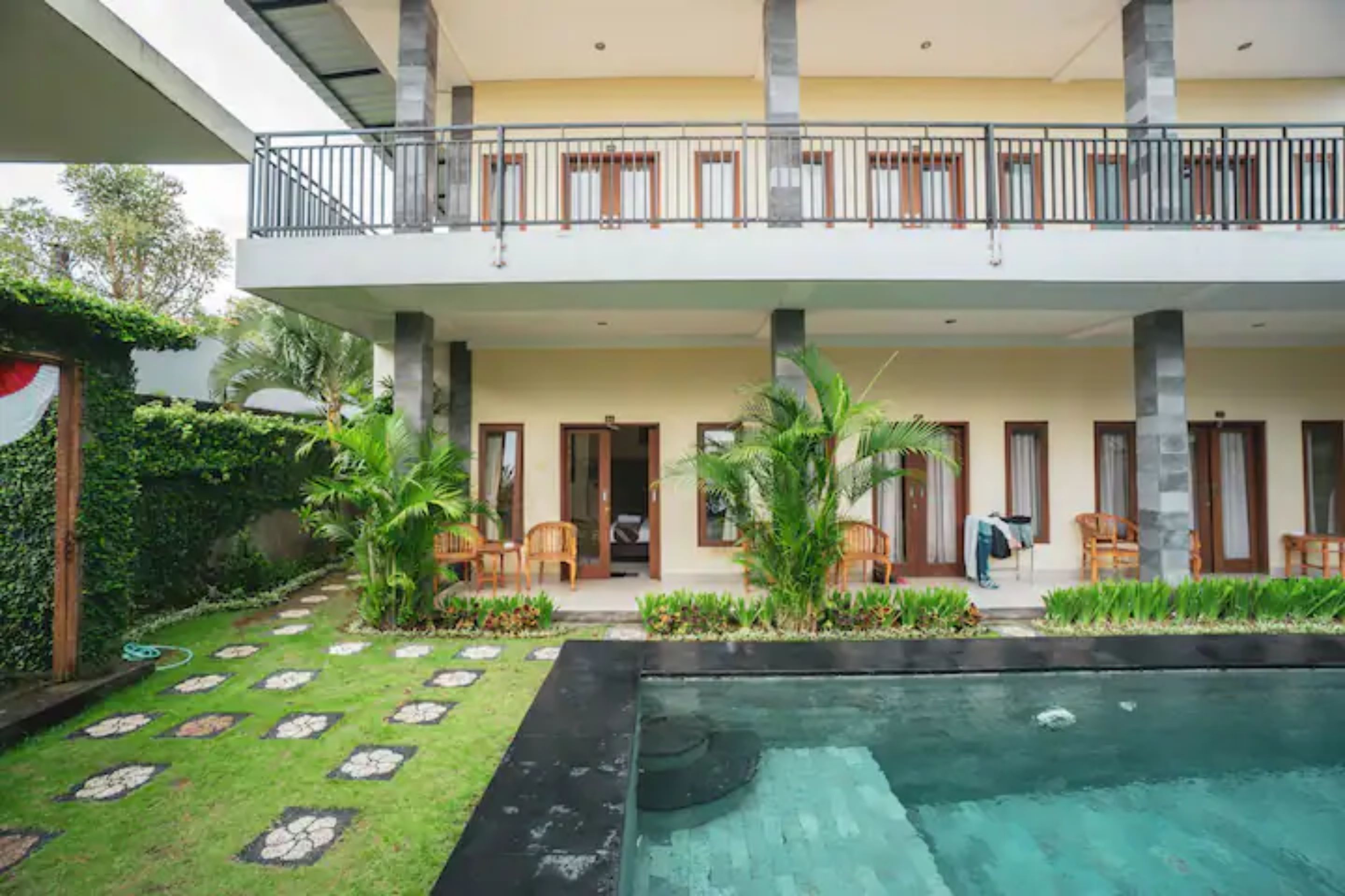A two-story building with a swimming pool, outdoor seating, and a balcony.