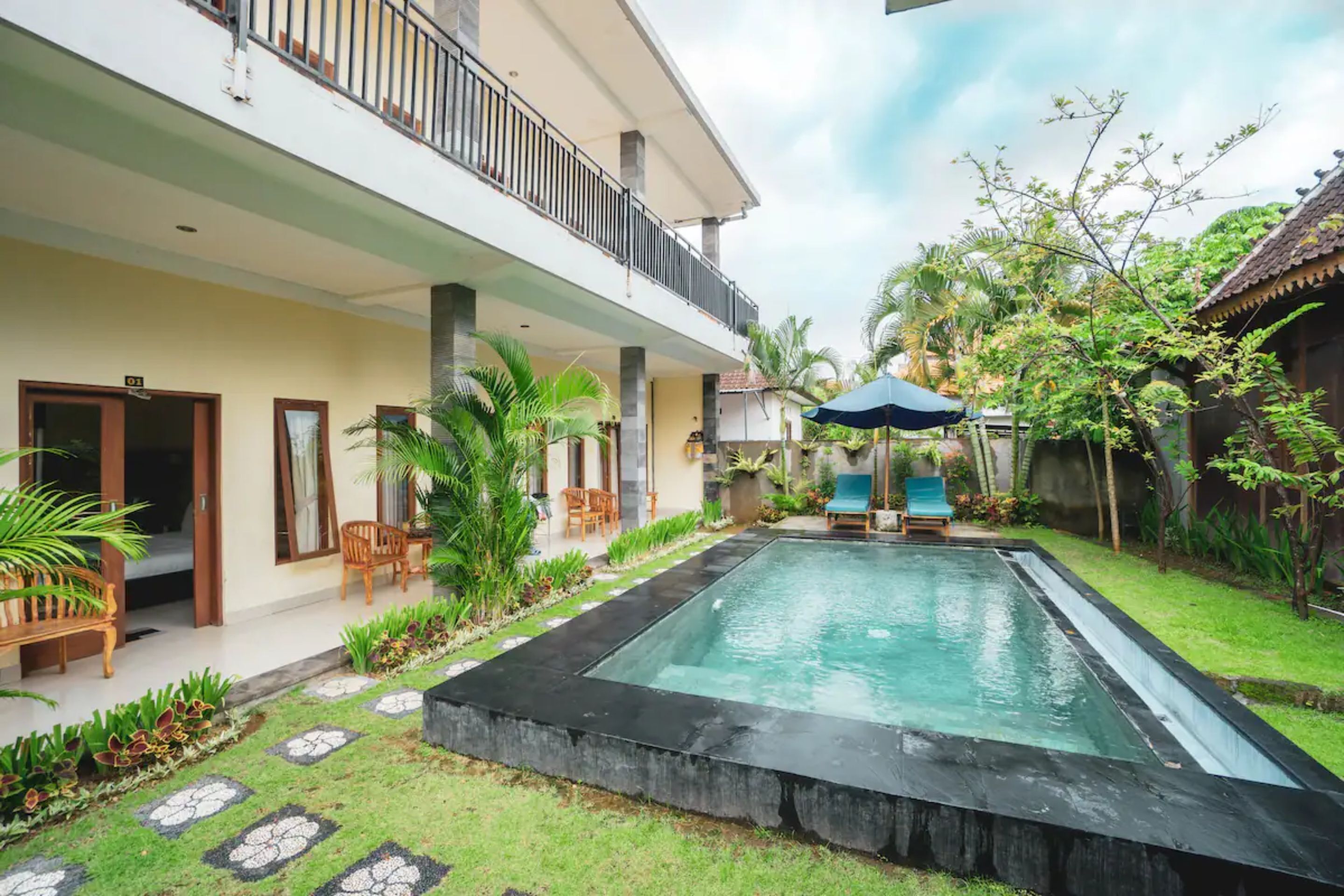 A two-story house with a swimming pool, outdoor furniture, and a garden.