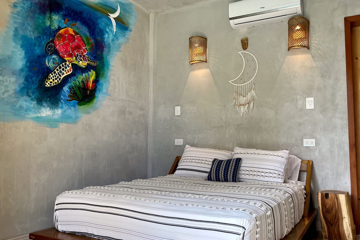 A bedroom with a bed, a wall mural, and wall-mounted lighting fixtures.