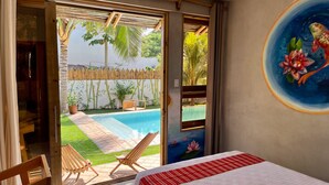Un dormitorio con vista a una piscina, una valla de bambú y un cuadro de flores.
