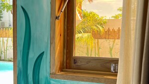 Una habitación con ventana que da a una piscina, un mural pintado con escenas submarinas y una puerta de madera.