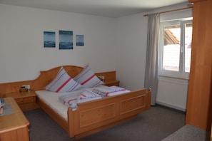 Un dormitorio con una cama de madera, una mesita de noche y una ventana con cortinas.